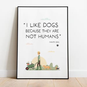 May include: A framed wall art print featuring the text "I LIKE DOGS BECAUSE THEY ARE NOT HUMANS" by Monty Don. The illustration depicts a person in a hat and green gardening gear pushing a wheelbarrow with a plant, accompanied by two dogs.