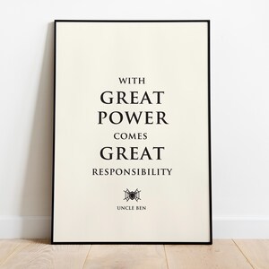 May include: A rectangular wall art print in a thin black frame featuring a cream-colored background with black text that reads: WITH GREAT POWER COMES GREAT RESPONSIBILITY. Below the text is a small black spiderweb icon and the name UNCLE BEN.