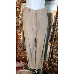 May include: A pair of light brown suede pants with a straight leg fit. The pants have a zipper fly and button closure.