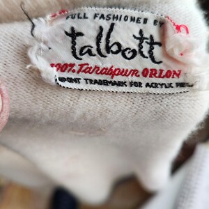Puede incluir: Su&eacute;ter blanco con una etiqueta blanca que dice "FULL FASHIONED BY Talbott 100% Tarabpun ORLON DUPONT TRADEMARK FOR ACRYLIC FIBER"