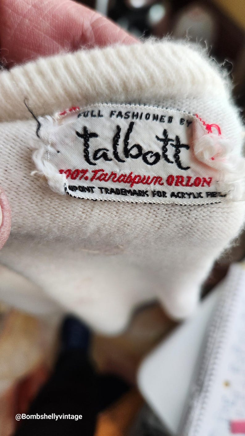 Puede incluir: Su&eacute;ter blanco con una etiqueta blanca que dice "FULL FASHIONED BY Talbott 100% Tarabpun ORLON DUPONT TRADEMARK FOR ACRYLIC FIBER"