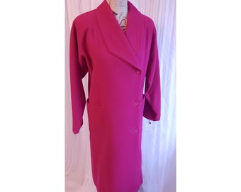 May include: A long, magenta-colored coat with a wide lapel collar and two rows of buttons. The coat has long sleeves and two front pockets. The coat is displayed on a mannequin.