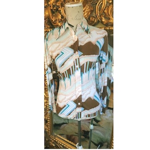 Puede incluir: Camisa vintage con estampado geométrico retro en marrón, blanco y turquesa. La camisa de manga larga se exhibe en un maniquí. Tiene cuello y una silueta entallada, perfecta para un look vintage único.