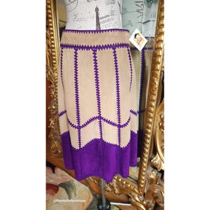 May include: A suede skirt with a purple trim. The skirt is a-line and has a high waist. The skirt is made of a soft, supple suede and is perfect for a vintage look.