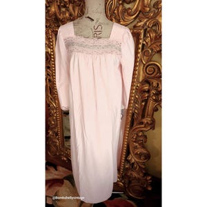 Könnte beinhalten: Ein rosafarbenes Nachthemd mit einer Spitzenborte am Ausschnitt und an den Ärmeln. Das Nachthemd ist lang und fließend und wird auf einer Schaufensterpuppe präsentiert.