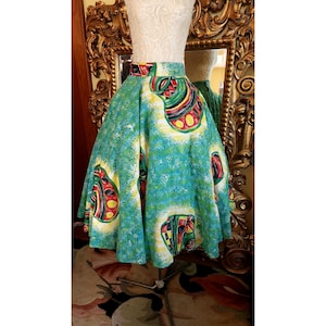 Op de afbeelding: Een volle cirkelrok met een abstracte print in groen, wit, rood en geel. De rok heeft een hoge taille en is gemaakt van een lichtgewicht stof.