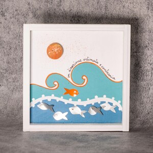 Könnte beinhalten: Quadratische, weiß gerahmte Kunst mit maritimem Thema. Das Kunstwerk zeigt eine orangefarbene Sonne, einen stilisierten orangefarbenen Fisch und eine blau-weiße Meereslandschaft mit mehreren Fischen. Der Text "in direzione ostinata e contraria" ist auf dem Kunstwerk geschrieben.