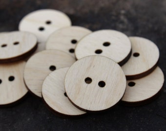 May include: A pile of wooden buttons with two holes each. The buttons are light brown and have a smooth, natural finish.