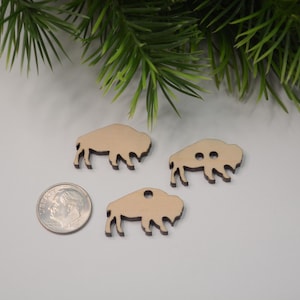 May include: Three unfinished wooden buffalo silhouette ornaments. The ornaments are approximately the size of a US quarter.