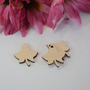 May include: Four unfinished wooden ivy leaf shapes. The leaves are light brown and have a hole at the top for hanging.