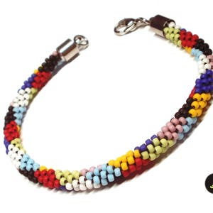 May include: A colorful beaded bracelet with a silver clasp. The bracelet is made of small, round beads in various colors, including red, yellow, blue, green, and white.