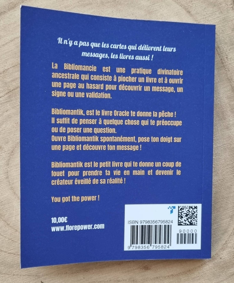 Może przedstawiać: Niebieska książka zatytułowana "Bibliomantik" z białym tekstem. Tylna okładka zawiera francuski tekst opisujący cel książki jako narzędzia wr&oacute;żbiarskiego. Zawiera numer ISBN, cenę i adres strony internetowej.
