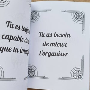 Może przedstawiać: Otwarta książka z białymi stronami. Lewa strona zawiera tekst "Tu es toujours capable de plus que tu imagi". Prawa strona zawiera tekst "Tu as besoin de mieux t'organiser". Obie strony mają dekoracyjne czarno-białe wzory narożne.