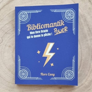 Może przedstawiać: Niebieska książka z tytułem "Bibliomantik" i słowem "POWER" w złotym kolorze. Okładka przedstawia złoty błyskawicę i gwiazdy. Nazwisko autora, Flore Cuny, znajduje się na dole. Książka ma dekoracyjne białe obramowania.