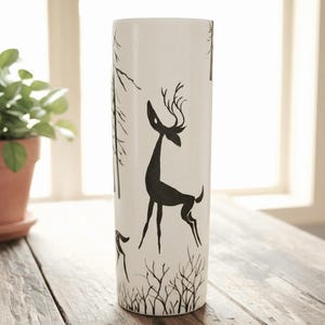 May include: A set of three ceramic mugs with a speckled, matte finish. The mugs are in shades of cream, light gray, and dark gray. Each mug has a simple, minimalist design and a rounded handle. The mugs are likely for coffee or tea.