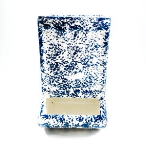 May include: A rectangular ceramic match holder with a speckled blue and white pattern. The holder has a rectangular opening at the bottom. The design is reminiscent of vintage kitchenware.