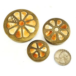 May include: Three antique brass boxes with a floral design, featuring cream and orange segments. A US quarter is included for size comparison. The boxes are arranged in a group on a white surface.
