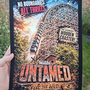 May include: A rectangular poster featuring a wooden roller coaster descending a steep track. Text reads: NO BOUNDARIES. ALL THRILLS, THE LEGENDARY WOODEN COASTER!, Walibi UNTAMED, FEEL THE WILD, and Walibi BELGIUM. The image displays a sunset sky.