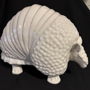 May include: White ceramic armadillo figurine with a textured shell and detailed legs.