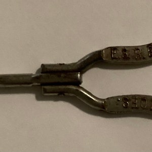 May include: A silver metal shoe horn with a hook on one end and the text "E. & R. BOOT SHOP, 808 WASHINGTON ST., SEATTLE" on the other end.