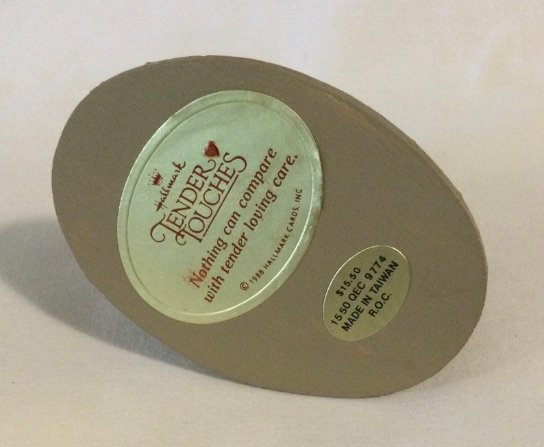 Puede incluir: Una base redonda de cer&aacute;mica beige con una pegatina dorada que dice "Hallmark Tender Touches Nothing can compare with tender loving care. &copy; 1988 Hallmark Cards, Inc. 15,50 &euro; 1550 QEC 9774 HECHO EN TAIW&Aacute;N R.O.C."