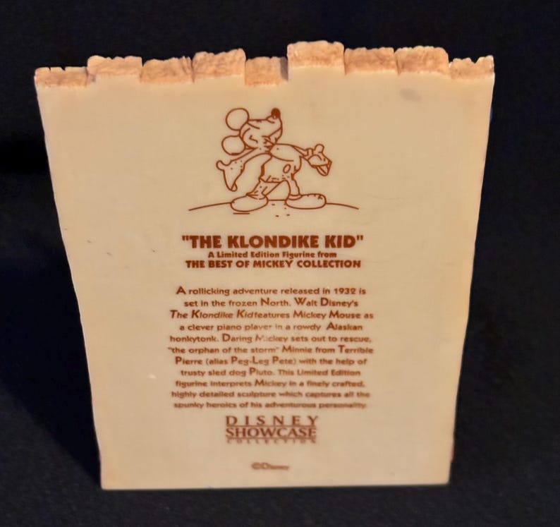 May include: A collectible figurine from the Disney Showcase Collection. The figurine features Mickey Mouse from "The Klondike Kid." The text on the figurine describes the 1932 adventure set in the frozen North. The figurine is a limited edition.