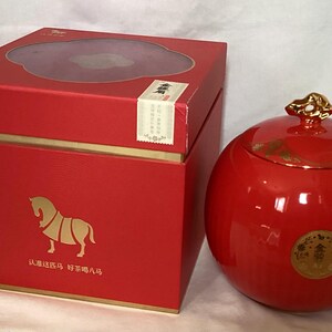 May include: A red round ceramic container with a gold lid and a gold design. The container is in a red box with a gold horse design and Chinese text. The box has a gold label with Chinese text.