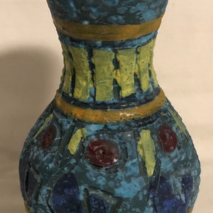 May include: A blue and yellow ceramic vase with a textured surface and geometric patterns. The vase has a wide mouth and a narrow base.