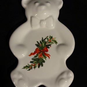May include: White ceramic bear-shaped dish with a green holly and red bow design.