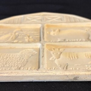 Puede incluir: Molde de mantequilla rectangular de color crema, con cuatro dise&ntilde;os de animales: un pato, un cerdo, una oveja y una vaca. El molde tiene una parte superior en forma de granero con detalles de entramado. Dise&ntilde;o r&uacute;stico y vintage.