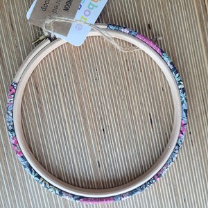 Peut inclure: Un cercle &agrave; broder en bois recouvert d'un tissu floral. Le tissu est un m&eacute;lange de rose, de noir et de blanc.