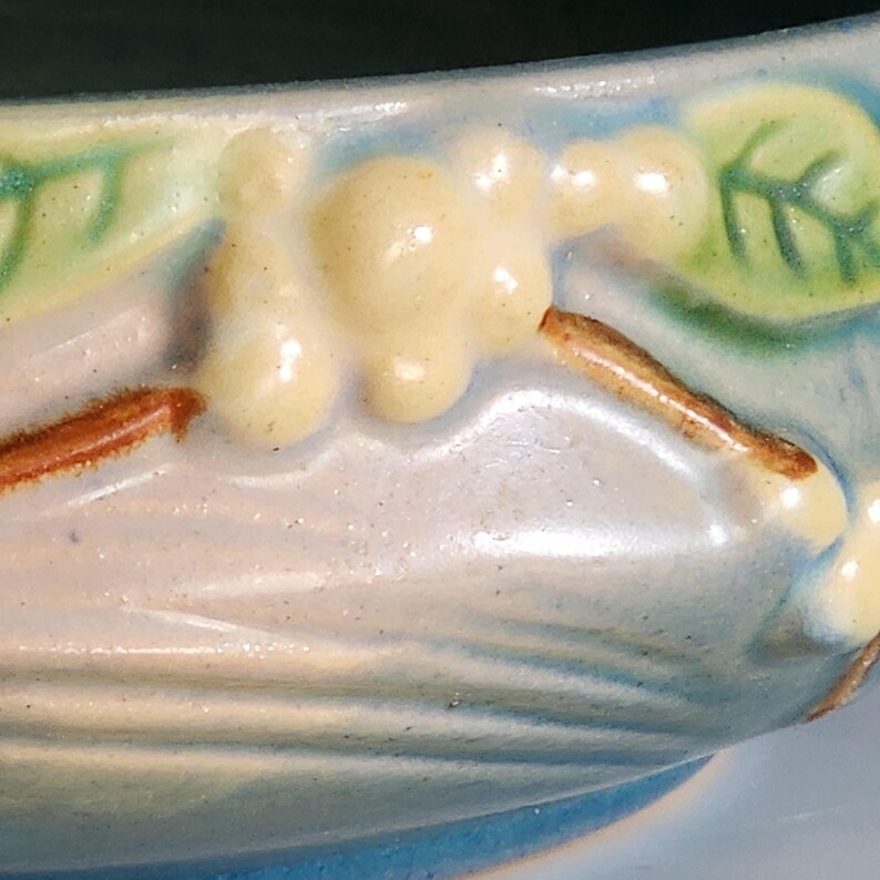 Puede incluir: Primer plano de un cuenco de cer&aacute;mica con un esmalte azul y un dise&ntilde;o floral. El dise&ntilde;o presenta flores amarillas con tallos marrones y hojas verdes.