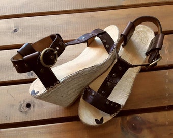 Sandals in T. T sandals with leather straps and rivets. Espadrille esparto wedges with wide strips and rivets. Spadrille leather with rivets