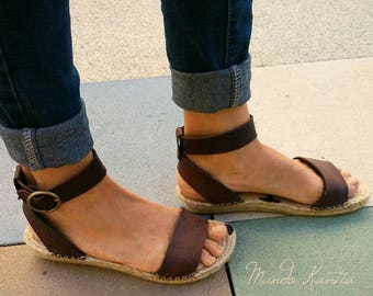 Barfuß-Espadrilles-Sandalen aus Leder und halbflacher Jutesohle mit breitem Knöchelriemen und runder Schnalle. Boho-Espadrille-Sandale