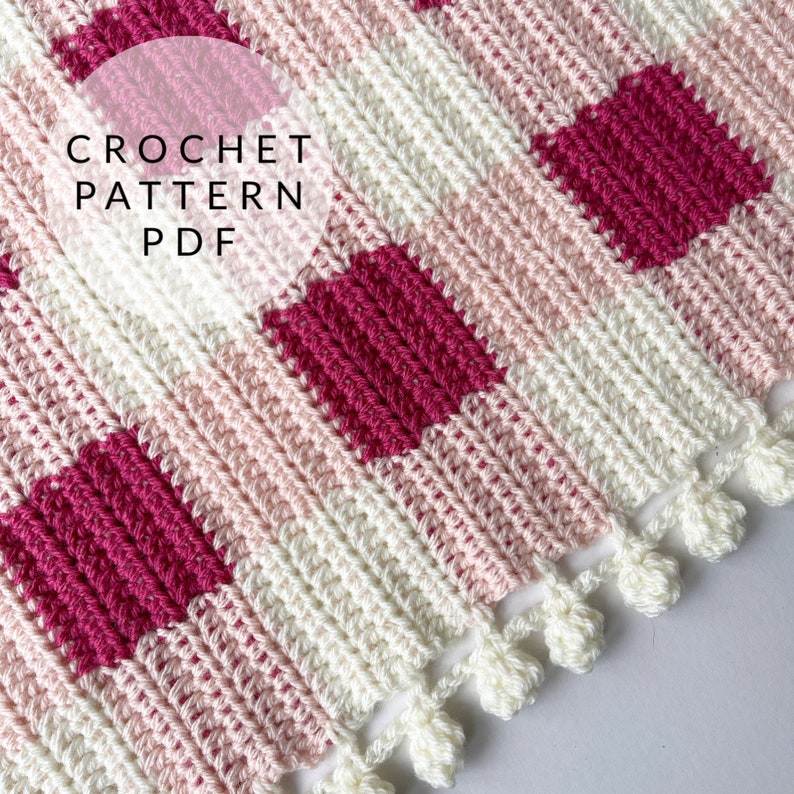 Pode incluir: Padr&atilde;o de croch&ecirc; PDF para um cobertor xadrez rosa e branco com uma borda de franjas.