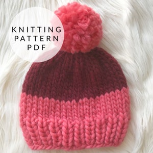 May include: Knitting pattern PDF for a burgundy and pink beanie with a fluffy pom pom.