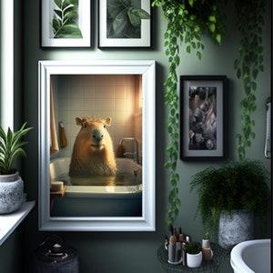 May include: A white framed picture of a capybara taking a bath in a white bathtub. The picture is hanging on a green wall with other framed pictures and plants.