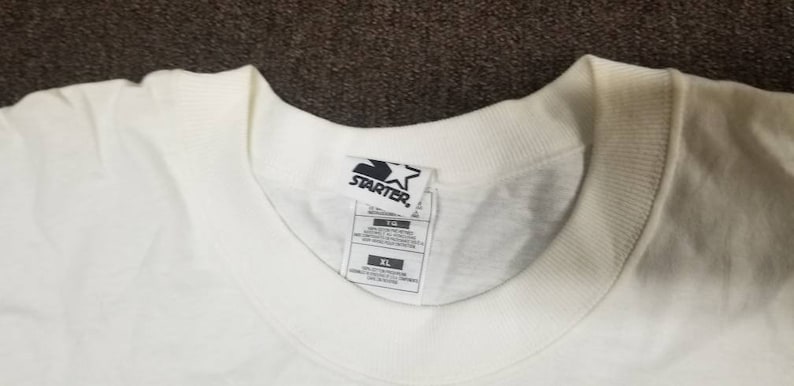 May include: White t-shirt with a black Starter logo and a white star. The tag says "XL" and "100% Cotton".