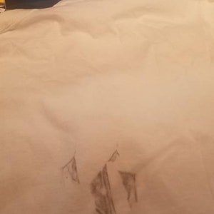 May include: A white t-shirt with a faint gray pencil drawing of a mountain range on the front.