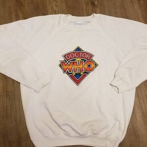 May include: White sweatshirt with a colorful Doctor Who logo printed on the front.