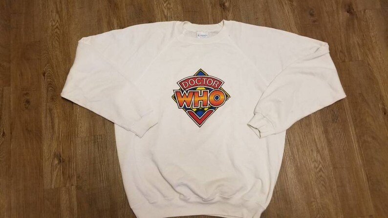 May include: White sweatshirt with a colorful Doctor Who logo printed on the front.