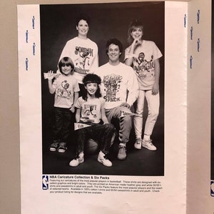 Op de afbeelding: Zwart-witfoto van een groep mensen die T-shirts dragen met karikaturen van beroemde basketbalspelers. De shirts hebben de tekst "Jordan", "Magic", "The Pistons", "Worthy" en "Classic Pack".