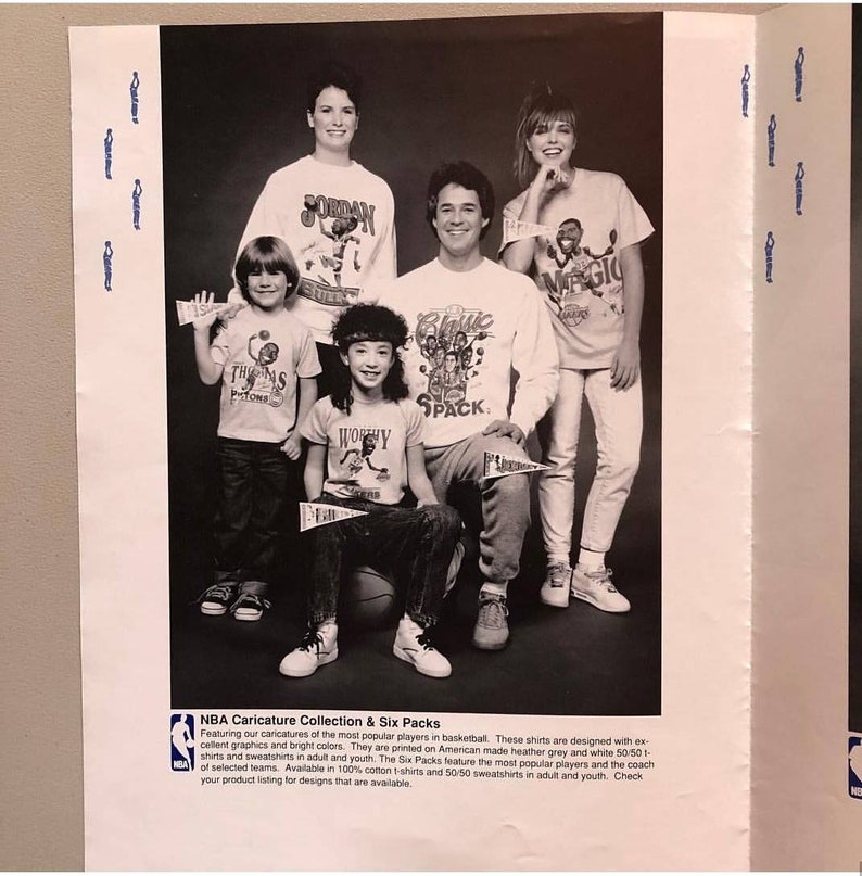 Op de afbeelding: Zwart-witfoto van een groep mensen die T-shirts dragen met karikaturen van beroemde basketbalspelers. De shirts hebben de tekst "Jordan", "Magic", "The Pistons", "Worthy" en "Classic Pack".