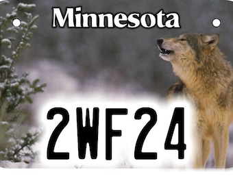 Puede incluir: Placa de matrícula con un lobo aullando en una escena de bosque nevado. La palabra "Minnesota" está en la parte superior, con el número de matrícula "2WF24" debajo. El fondo es un paisaje invernal borroso.