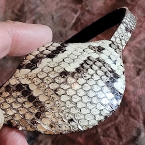 May include: A brown and white snakeskin eye patch with a black elastic band.