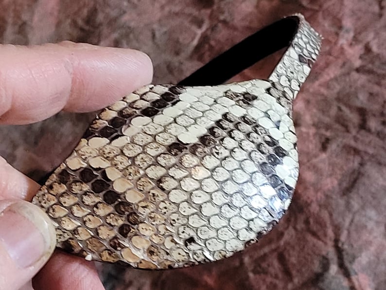 May include: A brown and white snakeskin eye patch with a black elastic band.