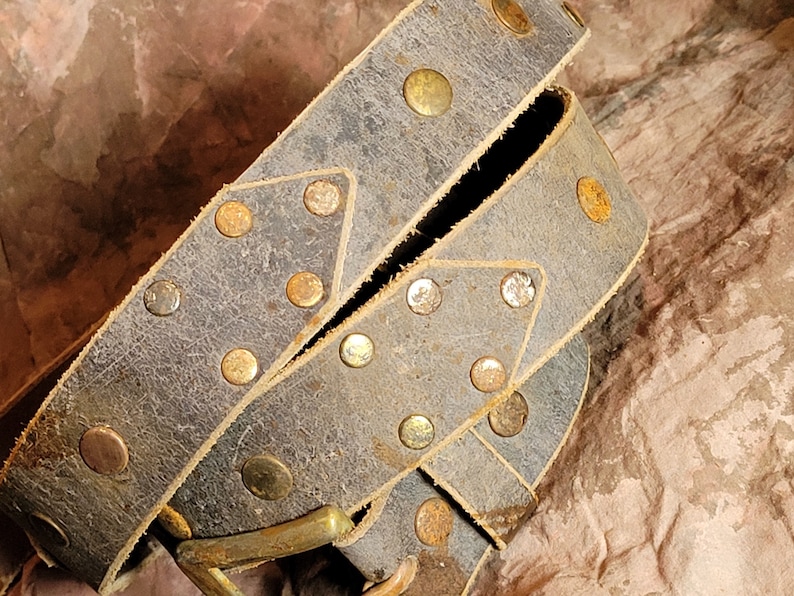 May include: A brown leather belt with brass studs. The belt is folded in half and the buckle is visible.