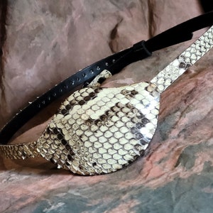 May include: A brown leather eye patch with a snakeskin design. The patch is attached to a black leather strap.