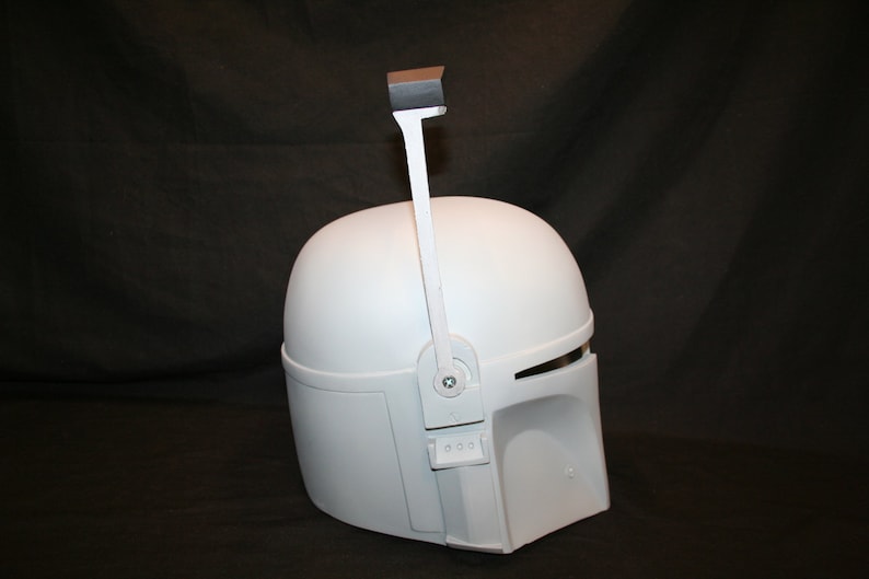 May include: A white Mandalorian helmet with a visor and a rangefinder. The helmet has a smooth, matte finish and is designed with angular shapes. The rangefinder is attached to the top of the helmet.