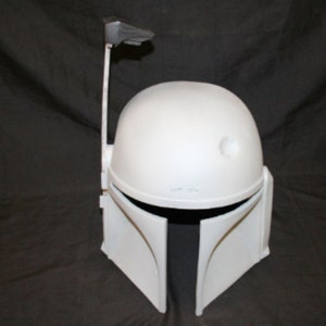 May include: A white Mandalorian helmet with a distinctive T-shaped visor and a rangefinder extending from the right side. The helmet has a rounded top and angled cheek plates, with a dark interior visible at the visor opening. A classic Star Wars costume accessory.